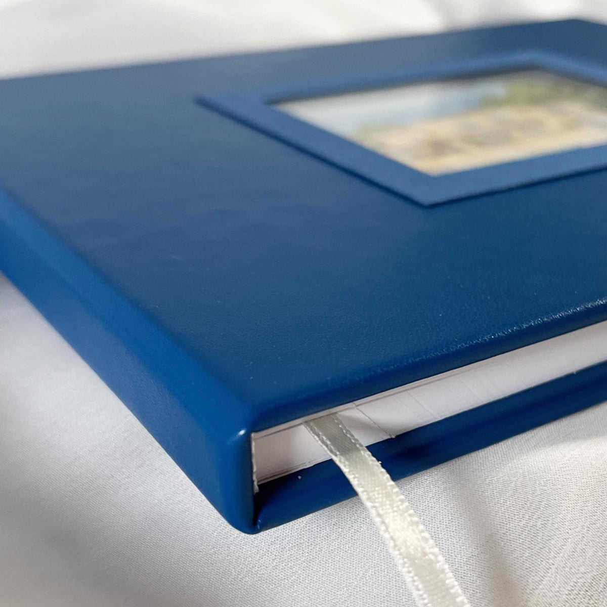 Custom-made blue leather wedding guest book with watercolor illustration of the venue.