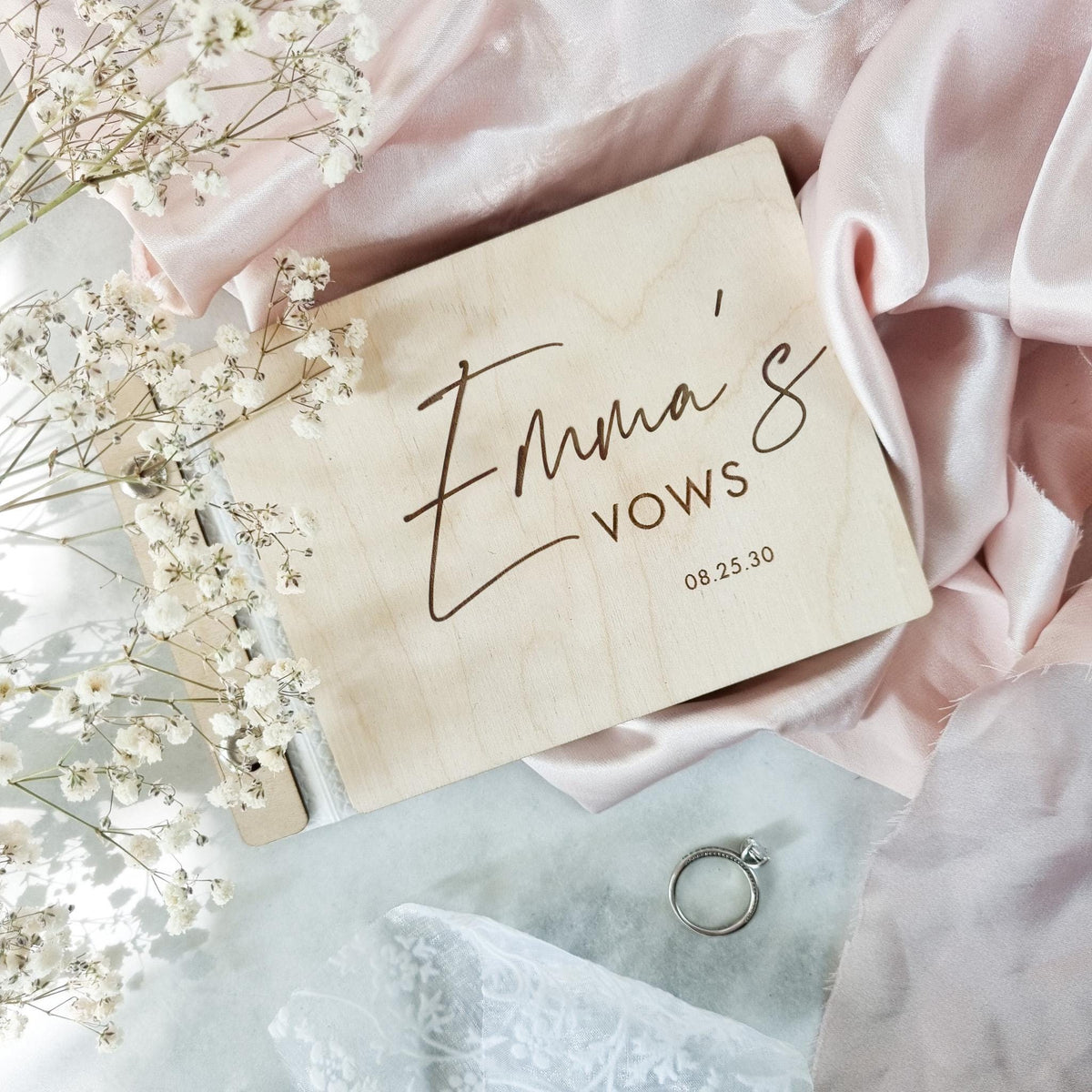 Custom "Emma’s Vows" vow book engraved with the groom’s name and wedding date on a natural wooden cover.