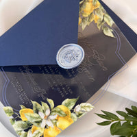 Summer wedding acrylic invitation with lemon artwork, Santorini-style tile insert in a blue envelope, and a personalized “WE DO” wax seal.