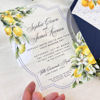 Transparent acrylic invitation with citrus design, accompanied by a blue envelope and decorative insert showcasing Santorini-inspired tiles and lemons.