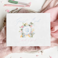 An elegant white velvet guest book designed with a personalized watercolor monogram of initials and floral motifs.