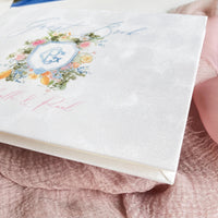 White velvet guest book with painted watercolor monogram and floral details.