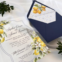 Clear acrylic wedding invitation featuring a lemon print, paired with a blue envelope containing an insert with Santorini tile and lemon motifs, finished with a blue wax seal reading “WE DO.”