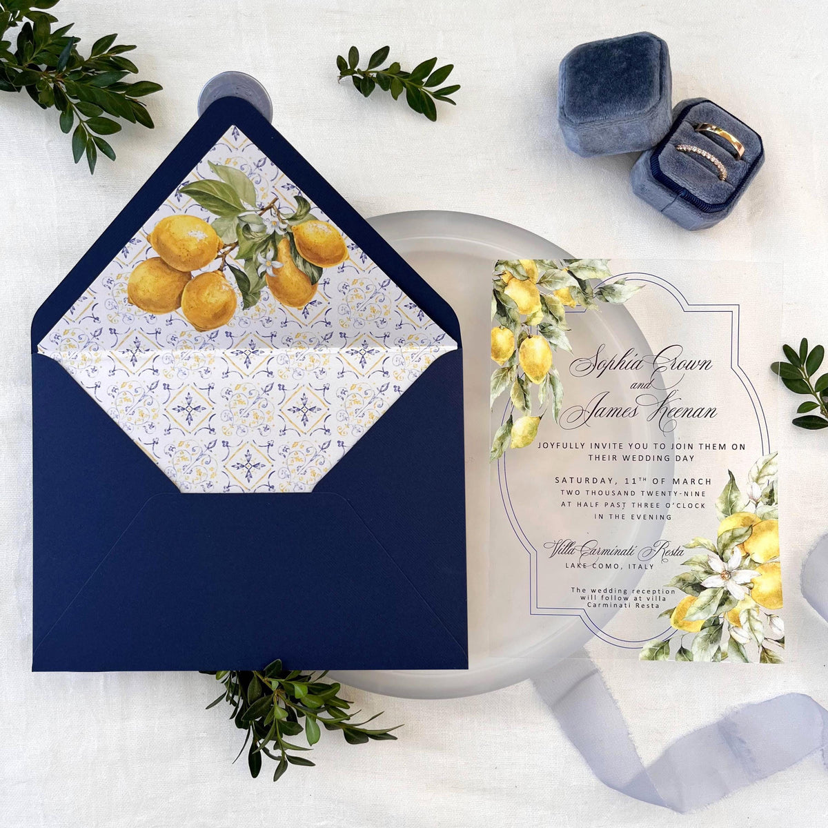 Destination wedding acrylic invitation featuring lemon illustrations, matched with a blue envelope and insert with Mediterranean tile design, finished with a blue wax seal.