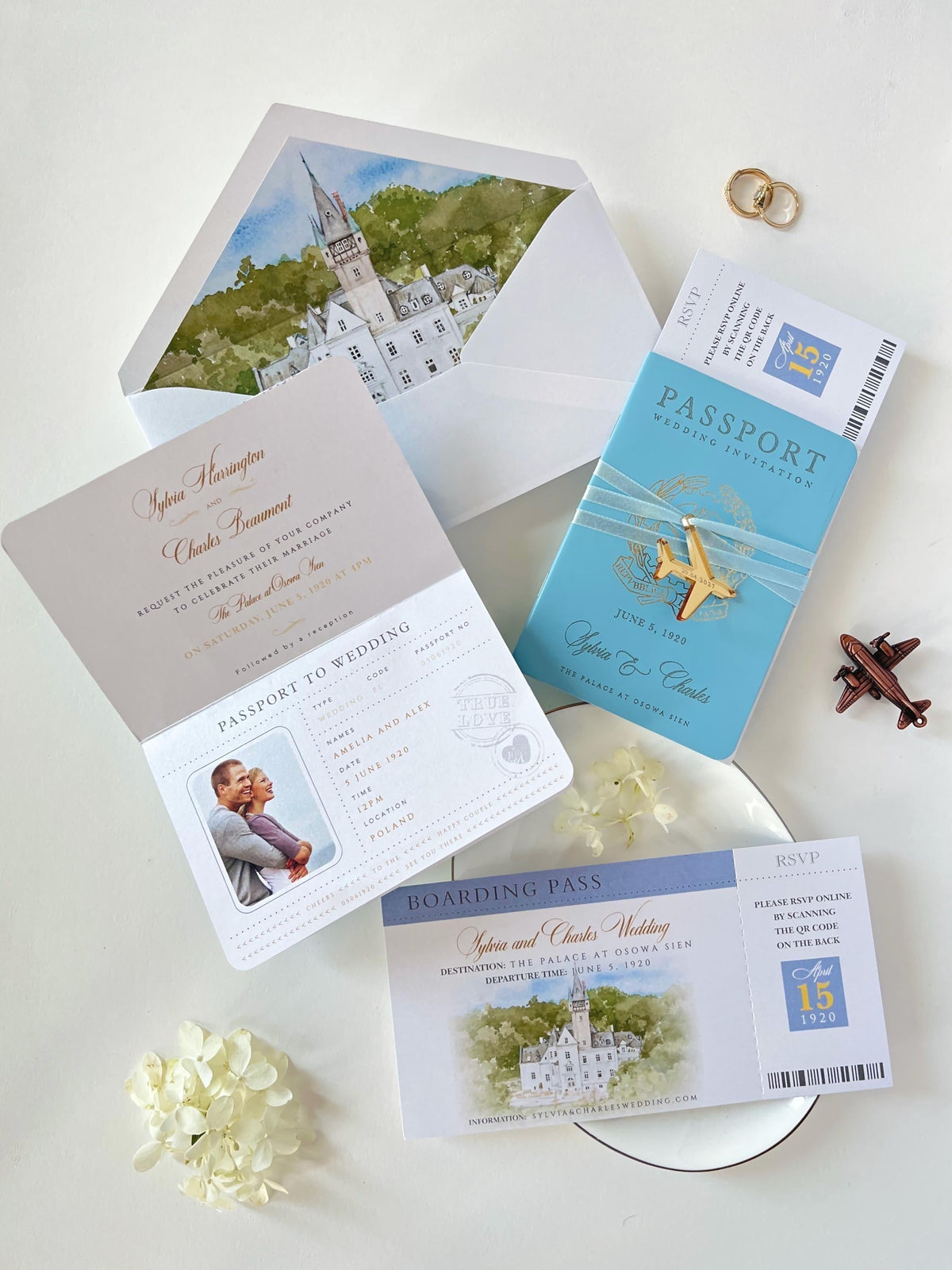 This wedding stationery suite features a blue faux leather passport invitation alongside a boarding pass RSVP card. The ensemble is completed by an elegant envelope lined with a custom watercolor illustration of the wedding venue's location.